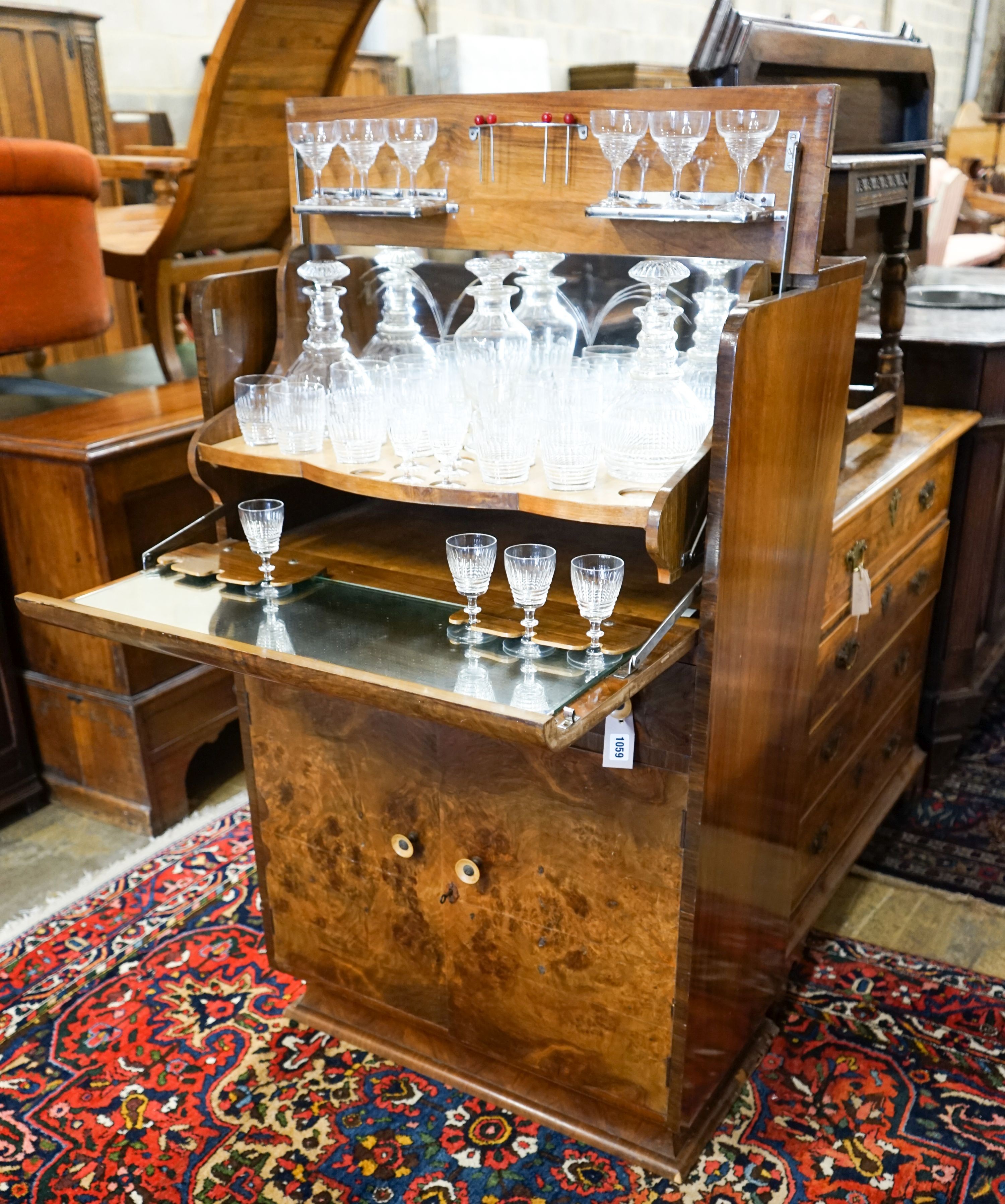 An Art Deco figured walnut and maple-lined cocktail cabinet, width 74cm, depth 41cm, height 121cm, containing a part suite of cut crystal table glass